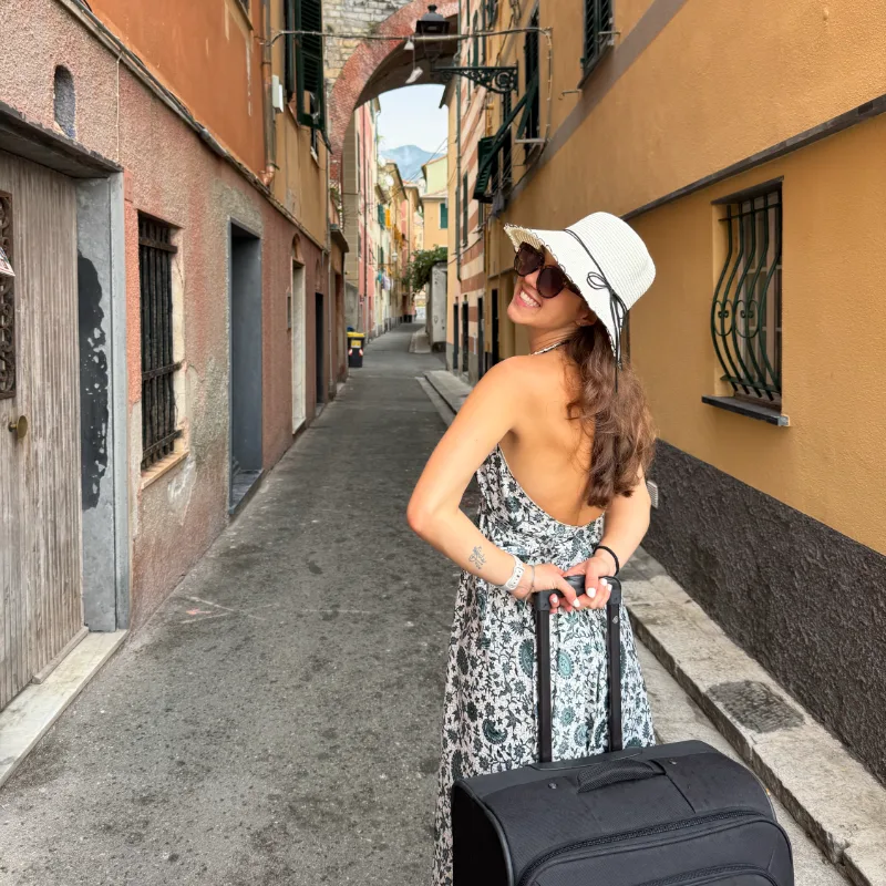 Kirsty Tornare with her suitcase in a narrow street, looking back over her shoulder